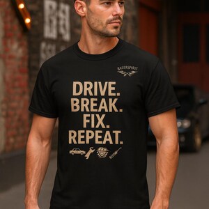 May include: Black t-shirt with the text "DRIVE. BREAK. FIX. REPEAT." in a tan color. The shirt also features car-related graphics and the "RACERSPIRIT" logo. The model is wearing the shirt.