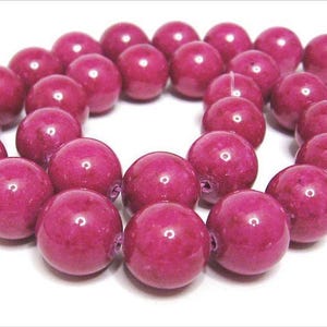 Pode incluir: Um fio de contas redondas de pedra preciosa rosa. As contas são lisas e têm um brilho ligeiro.