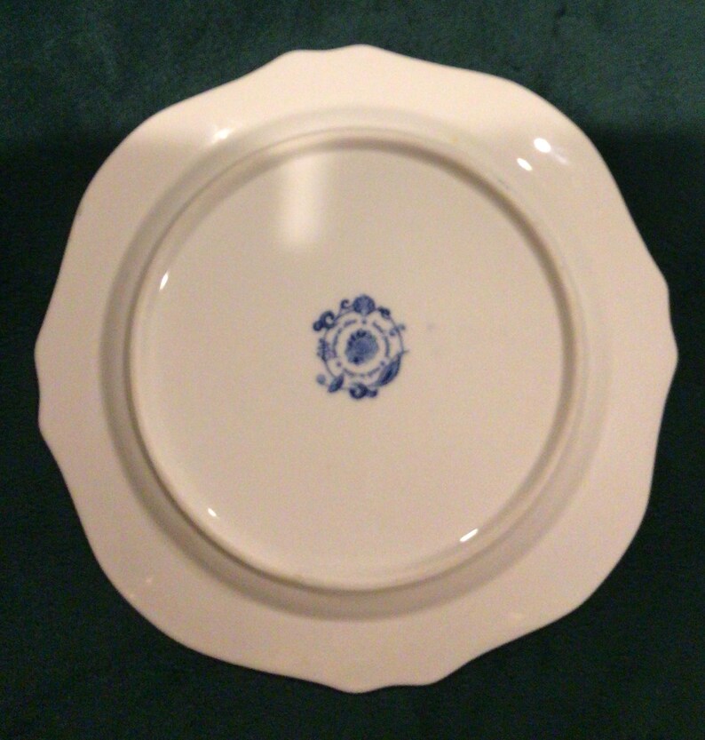 May include: White ceramic plate with a scalloped edge and a blue and white floral design on the bottom.