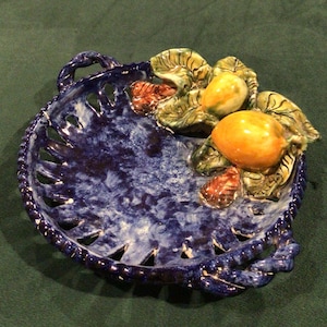 May include: A blue and white ceramic serving dish with two yellow lemons and green leaves. The dish has a rope-like border and cut-out designs.