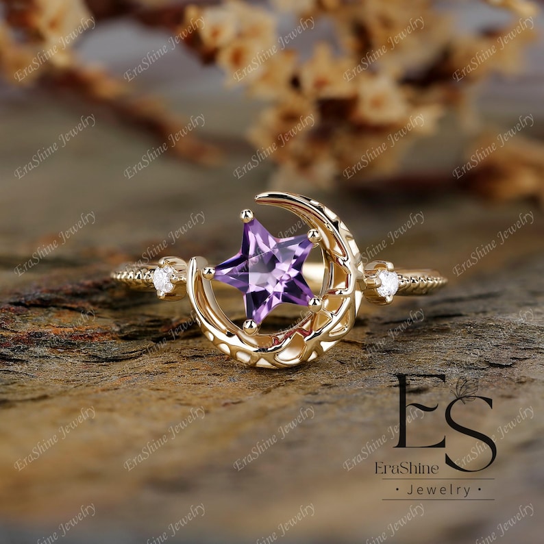 K&ouml;nnte beinhalten: Ein goldener Ring mit einem Halbmond-Design und einem lila sternf&ouml;rmigen Edelstein. Der Ring ist mit kleinen Diamanten auf der Band besetzt.