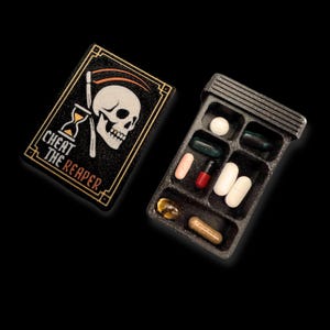 Pastillero calavera 'Cheat the Reaper' – caja de estilo gótico con calavera y guadaña 3D, regalo artístico y simbólico, formato grande