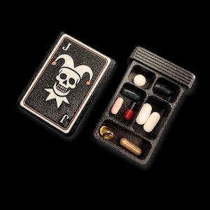 Pilulier artistique inspiré de la carte Joker – boîte à pilules originale avec crâne argenté, cadeau design à offrir ou à collectionner.