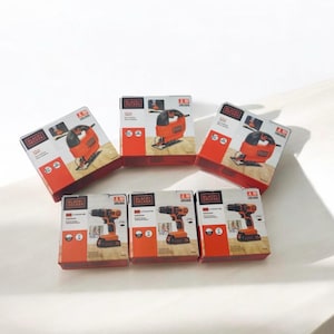 May include: A collection of new Black+Decker power tools in their packaging. The boxes are orange and black, with tool images. The tools include a jigsaw and a cordless drill, suitable for DIY projects around the home.