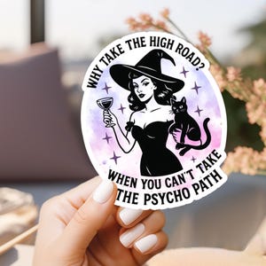 Puede incluir: Una pegatina con una ilustración retro de una mujer con sombrero de bruja, copa de vino y gato negro. El texto dice: "¿Por qué tomar el camino difícil? Cuando no puedes tomar el camino psicópata."