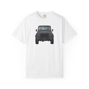 May include: White t-shirt featuring a black illustration of a Land Rover Defender SUV. The vehicle is centered on the shirt, showcasing its front profile. The shirt has a crew neck and short sleeves.
