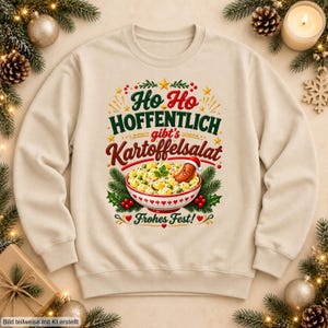 May include: A beige crewneck sweatshirt featuring a graphic of a bowl of potato salad with a sausage wearing a Santa hat. The text reads Ho Ho HOFFENTLICH gibt's Kartoffelsalat Frohes Fest! surrounded by pine branches, berries, and stars.