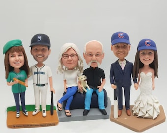 Op de afbeelding: Een set van zes op maat gemaakte bobbleheads, elk met een unieke persoonlijkheid en outfit. De bobbleheads staan op een honkbalveld basis. De bobbleheads dragen een verscheidenheid aan kleding, waaronder een honkbaluniform, een trouwjurk, een pak en casual kleding. Eén bobblehead houdt een honkbalknuppel vast en een ander houdt een kleine hond vast.