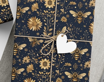 May include: Gift-wrapped presents with navy blue paper featuring a gold floral and bee pattern. Each package is tied with twine and a white tag. A spool of twine, scissors, and blank tags are also visible.
