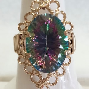 May include: A gold ring with a large, oval-shaped, iridescent gemstone set in a delicate, intricate design.