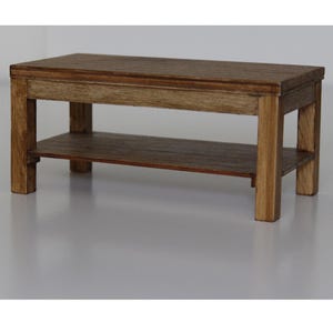 Puede incluir: Una mesa de centro de madera con un estante inferior. La mesa es de color marrón oscuro y tiene una forma rectangular.