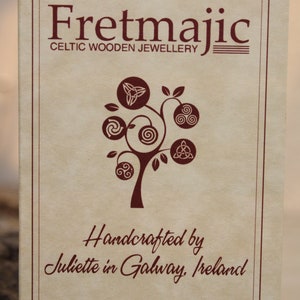 May include: A brown paper card with the text "Fretmajic Celtic Wooden Jewellery" and a tree with Celtic knot designs. The text "Handcrafted by Juliette in Galway, Ireland" is also on the card.
