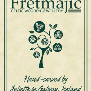May include: A logo for Fretmajic Celtic Wooden Jewellery, featuring a stylized tree with Celtic knot designs on each branch. The text "Hand-carved by Juliette in Galway, Ireland" is below the tree.