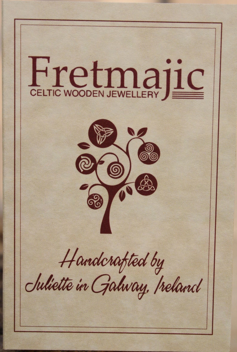 Pu&ograve; includere: Un cartoncino marrone con il testo "Fretmajic Celtic Wooden Jewellery" e un albero stilizzato con nodi celtici. Il testo "Handcrafted by Juliette in Galway, Ireland" &egrave; anche sul cartoncino.