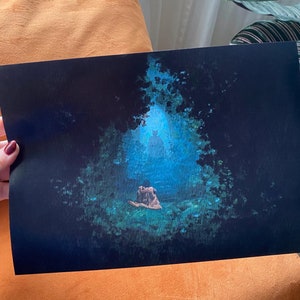 May include: A digital art print of a person sitting in a forest with a blue glow behind them. The print is on black paper and has a watercolor effect.