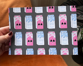 May include: A repeating pattern of cartoon milk cartons with different facial expressions. The cartons are pink, blue, and white with the word "milk" printed on them. The background is gray.
