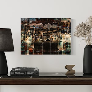 May include: A contemporary living room setup with a dark wood table and a black marble surface. It displays a black lamp, books, a gold sculpture, and a black vase with dried flowers. A cityscape artwork is mounted on the white wall.