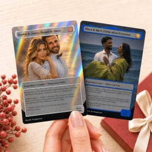 May include: Two rectangular trading cards with holographic borders. The left card shows a couple with the text 'Sophie & James, Bound by Dawn' and 'Legendary Couple - Santorini Cliffs'. The right card shows a couple at the beach with the text 'Maya & Ravi, Liebe ohne Grenzen' and 'Legendäres Paar - Küste von Goa'.