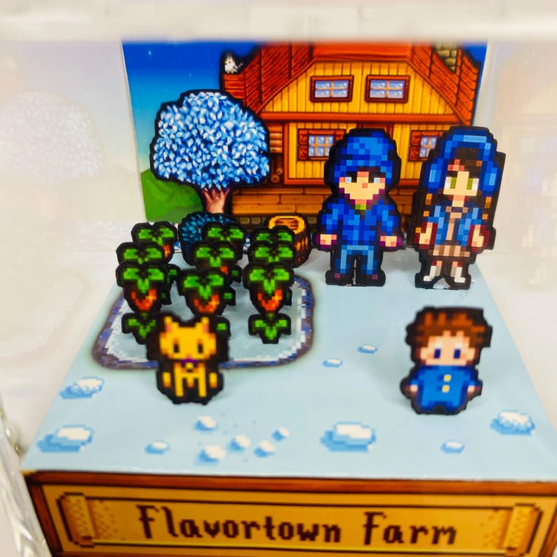 May include: A diorama featuring pixelated characters and elements from a farming game. The scene includes a house, a blue tree, crops, and characters in blue outfits. The base of the diorama reads "Flavortown Farm".