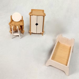 May include: Miniature wooden dollhouse furniture set. Includes a vanity with a round mirror, a small chair, a wardrobe with two doors, and a bed frame. The furniture is made of light-colored wood and has a simple, classic design.