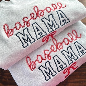 May include: Two gray sweatshirts with red embroidered baseball stitching and the text "Baseball Mama" in black and white.