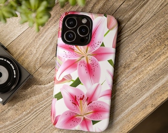 Puede incluir: Una funda de teléfono blanca con un diseño floral rosa y blanco. La funda presenta un primer plano de lirios rosas con detalles blancos.