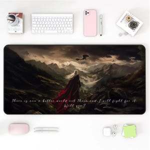 May include: A large rectangular desk mat featuring a dramatic landscape with a figure in a red cloak. The image includes a mountain range, a flying creature, and the text: "There is now a better world out There and I will fight for it. Will you?"