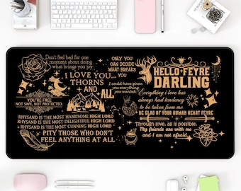 May include: Black rectangular desk mat with gold text and illustrations. The mat features phrases like "Hello Feyre Darling" and "I love you... Thorns and All." Other items on the desk include a white keyboard, a pink phone, and a white mouse.