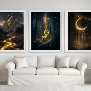 Puede incluir: Tres impresiones art&iacute;sticas enmarcadas con paisajes de fantas&iacute;a. Una representa una cordillera con un r&iacute;o dorado, otra un ciervo en un bosque con luz dorada y la tercera una luna creciente con estrellas doradas. Las impresiones se exhiben sobre un sof&aacute; blanco.
