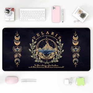 Könnte beinhalten: Eine schwarze und goldene Mausmatte mit einem himmlischen Design, das eine Bergkette, Sterne und Mondsicheln zeigt. Der Text "VELARIS CITY OF STARLIGHT" ist in einer dekorativen Schrift geschrieben. Das Zitat "To the stars who listen and the dreams that are answered" steht unter dem Design.
