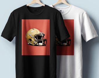 Könnte beinhalten: Zwei T-Shirts hängen an Holzbügeln. Ein schwarzes T-Shirt und ein weißes T-Shirt. Jedes Shirt hat eine Grafik eines goldenen American-Football-Helms auf rotem Hintergrund. Die Shirts sind kurzärmelig.