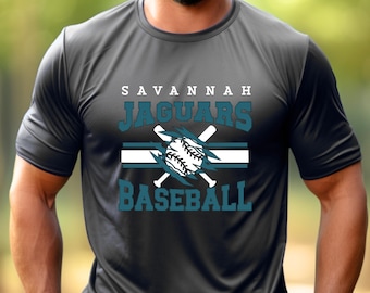 May include: A charcoal gray short-sleeve t-shirt featuring a graphic print with the text SAVANNAH JAGUARS BASEBALL. The design includes a white baseball, two crossed white baseball bats, and horizontal stripes in white and teal.
