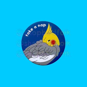 May include: A blue and white round button with the text "take a nap" and a cartoon illustration of a yellow and gray cockatiel sleeping.