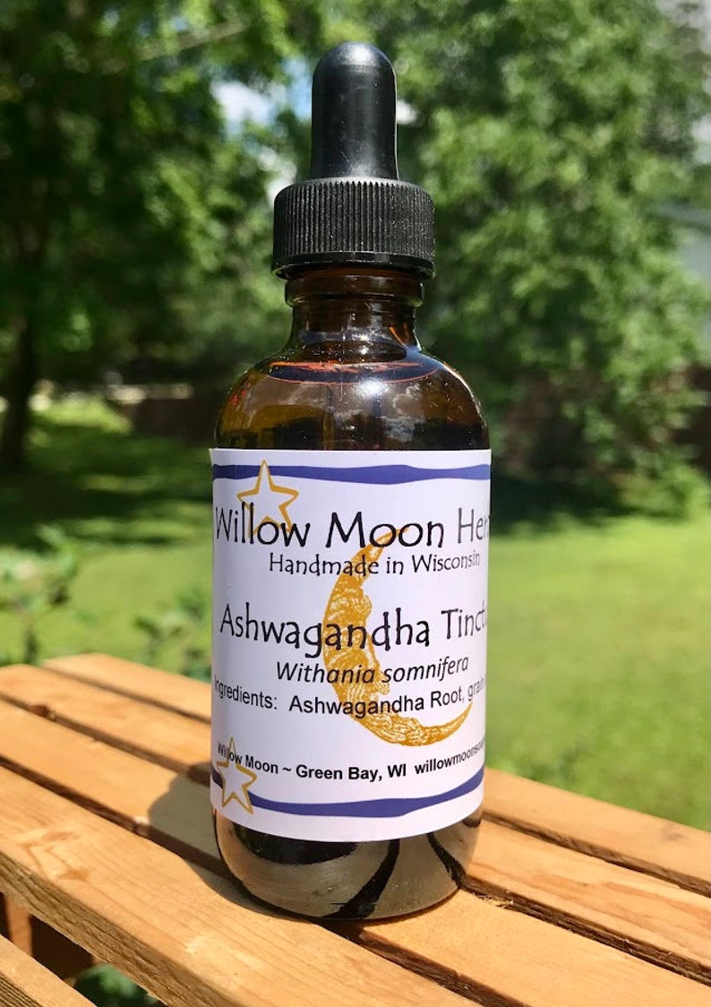 May include: A brown glass bottle with a dropper top and a white label that reads "Willow Moon Herbs Handmade in Wisconsin Ashwagandha Tincture Withania somnifera Ingredients: Ashwagandha Root, grain Willow Moon ~ Green Bay, WI willowmoonherbs.com"