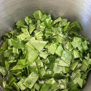 以下が含まれることがあります： 刻んだ緑の葉野菜でいっぱいになった大きなステンレス製の鍋