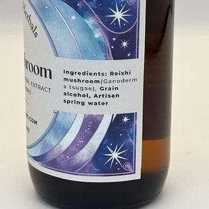 May include: A brown glass bottle with a white label featuring a blue and purple design with stars. The label reads "Herbals" and "Reishi mushroom (Ganoderm a tsugae), Grain alcohol, Artisan spring water".