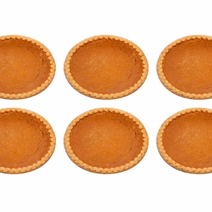 May include: Six empty, baked pie crusts with a golden-brown color and a crimped edge are arranged on a white background. The pie crusts are ready to be filled with a variety of fillings.