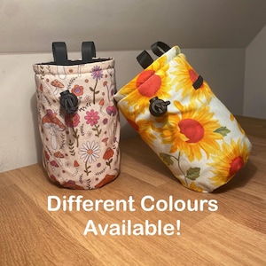 Puede incluir: Dos bolsas de tiza de tela con correas y cierres negros. Una bolsa presenta un fondo beige con estampados de setas y flores. La otra bolsa tiene un fondo blanco con grandes girasoles amarillos. El texto en la superficie dice "¡Diferentes colores disponibles!"