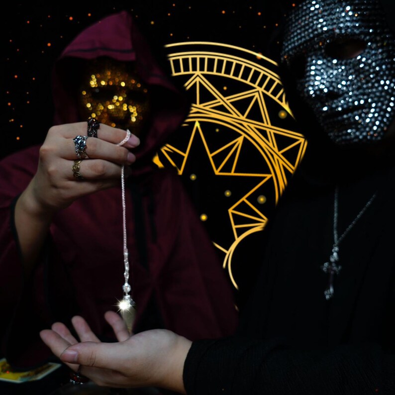 K&ouml;nnte beinhalten: Zwei Personen sind abgebildet, eine in einem burgunderfarbenen Kapuzenmantel und die andere mit einer glitzernden Maske. Ein Kristallpendel wird von der Person im Umhang gehalten, w&auml;hrend die andere die Hand ausstreckt. Ein goldenes geometrisches Design befindet sich im Hintergrund.