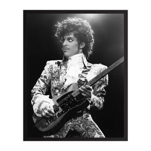 Peut inclure: Photographie en noir et blanc d'un musicien jouant de la guitare. Le musicien porte un costume à motifs et une chemise à volants. L'image est encadrée en noir, avec un projecteur brillant d'en haut.