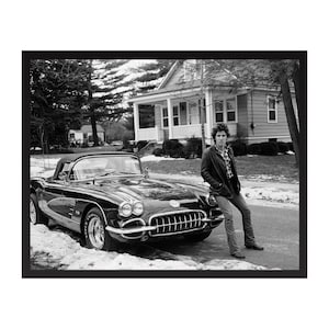 Puede incluir: Fotografía en blanco y negro de un coche descapotable negro clásico aparcado en una calle nevada. Una persona se apoya en el coche. El coche tiene detalles cromados y una capota negra.