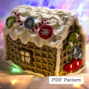 May include: A crocheted gingerbread house with white icing and candy decorations. The house is brown and has a window. The text "PDF Pattern" is visible at the bottom of the image.