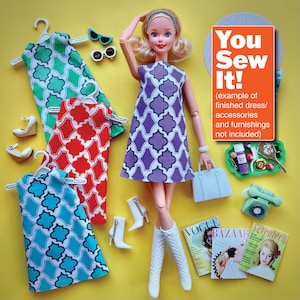 May include: A doll wearing a purple and white geometric patterned dress and white boots. The doll is holding a white handbag. The image also includes three dresses with geometric patterns in green, red, and blue, a pair of sunglasses, a telephone, and magazines.
