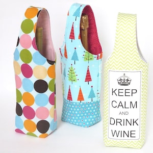 May include: Three fabric wine bottle carriers. The first is blue with a white polka dot pattern and a Christmas tree design. The second is green with a chevron pattern and the text "Keep Calm and Drink Wine". The third is blue with a white polka dot pattern and a Christmas tree design.