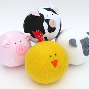 May include: Four plush toy animal balls. A pink pig, a black and white cow, a white sheep, and a yellow chick.