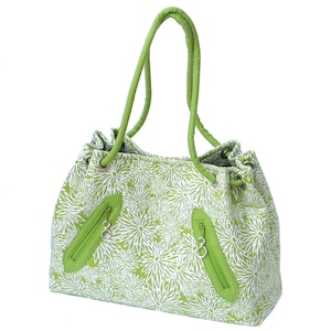 May include: A green tote bag with a white floral pattern. The bag has two zippered pockets on the front and two handles.