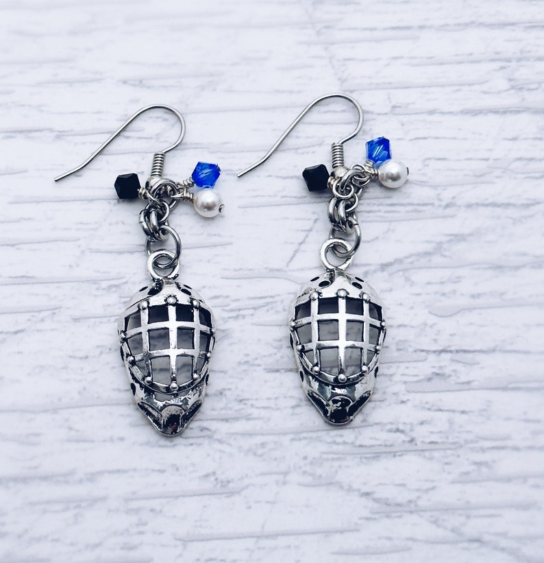 May include: A pair of silver earrings with a cage design. Each earring has a small chain with blue and white beads.