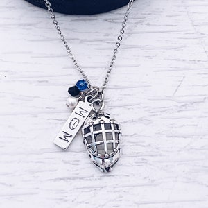 Puede incluir: Un collar de plata con un dije de m&aacute;scara de hockey, una etiqueta de plata que dice "MOM" y cuentas azules, negras y blancas.