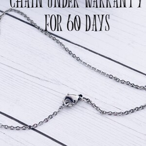 Puede incluir: Un collar de cadena de plata con un cierre de langosta. La cadena est&aacute; sobre una superficie de madera blanca. El texto "CHAIN UNDER WARRANTY FOR 60 DAYS" es visible sobre la cadena.