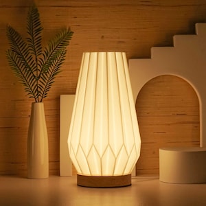 May include: A white table lamp with a pleated fabric shade. The lamp has a wooden base and is lit, casting a warm glow.